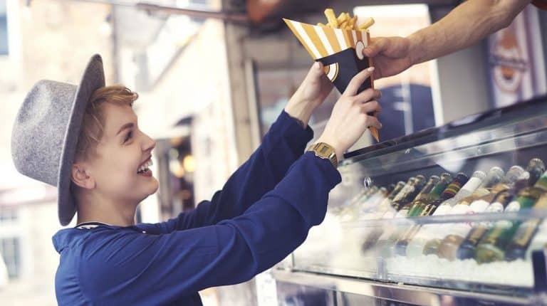 Young woman enjoying fries at a street food vendor.