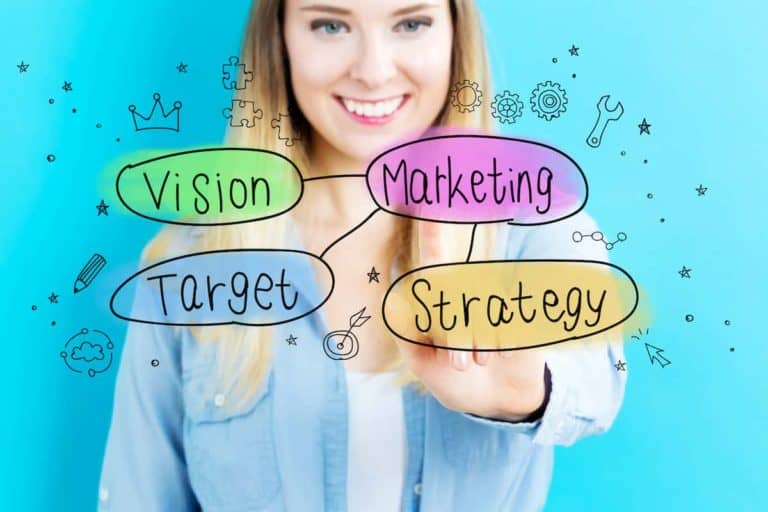 Woman drawing marketing concepts with colorful words on a blue background.