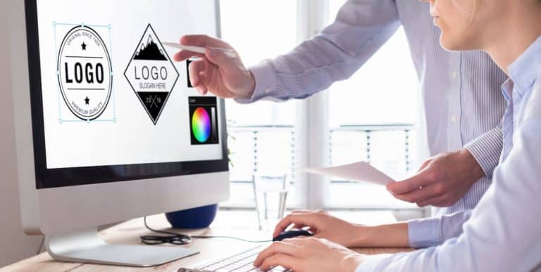 Business professionals designing logo concepts on computer screen for branding.