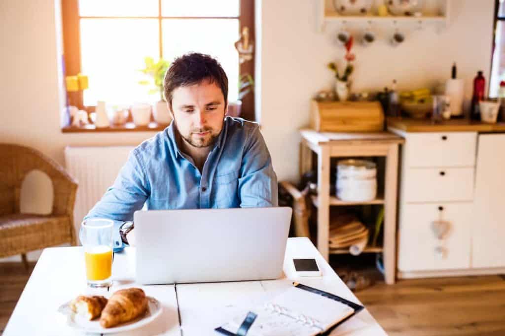 man sitting at computer at his kitchen table