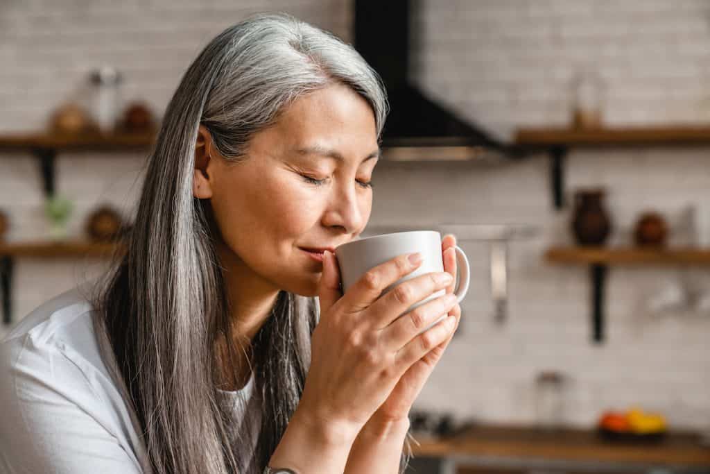 mature woman drinking hot coffee in the kitchen